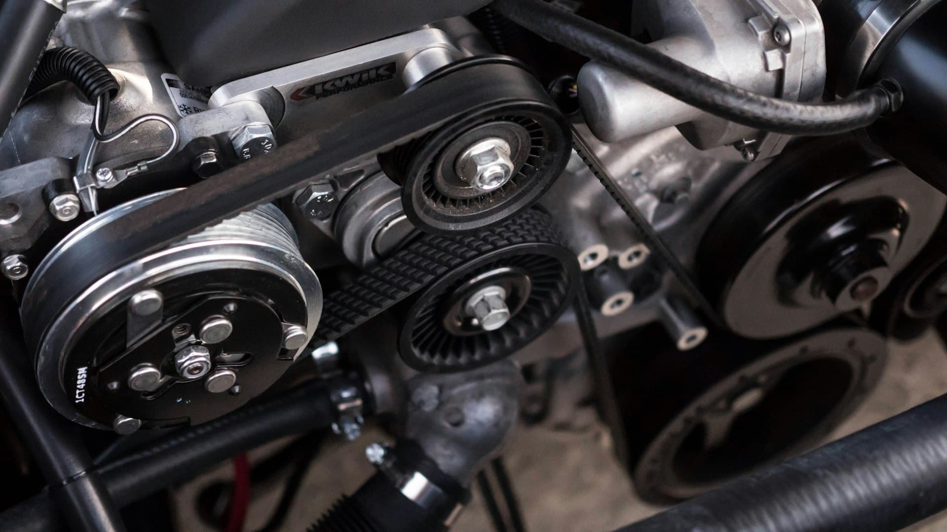 Close-up of an alternator, drive belt and pulleys in a car engine bay